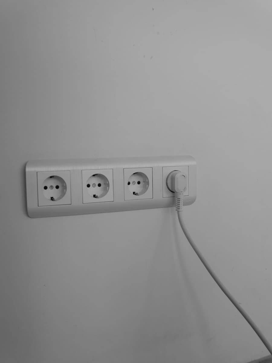 Dreifach-Steckdose sauber in einer hellen Wand montiert.