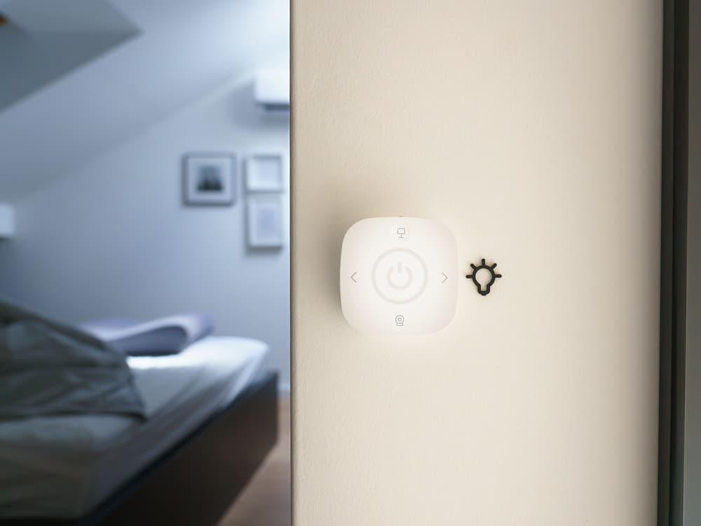 Wandtaster einer Smart-Home-Steuerung in einem hellen Schlafzimmer.