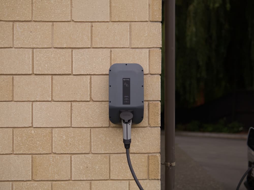 Wandladestation an einer Hauswand neben einer Garageneinfahrt.